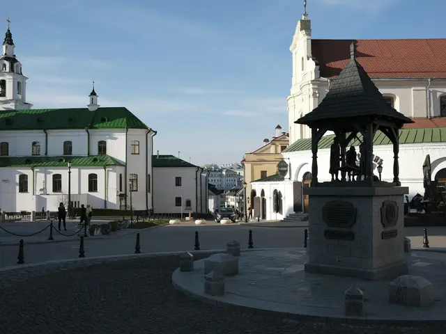 A quiet cobbled square in the Upper Town in low sun, with white baroque church towers and a pavilion of bronze figures
